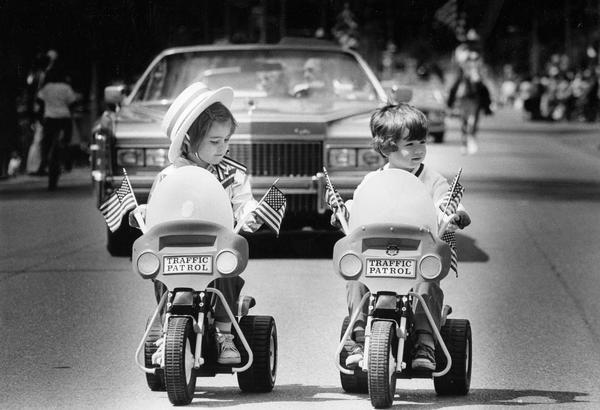 A pair of boy and girl toddlers lead a part of the 33rd annual Memorial Day Parade on flag-bedecked tricycles.