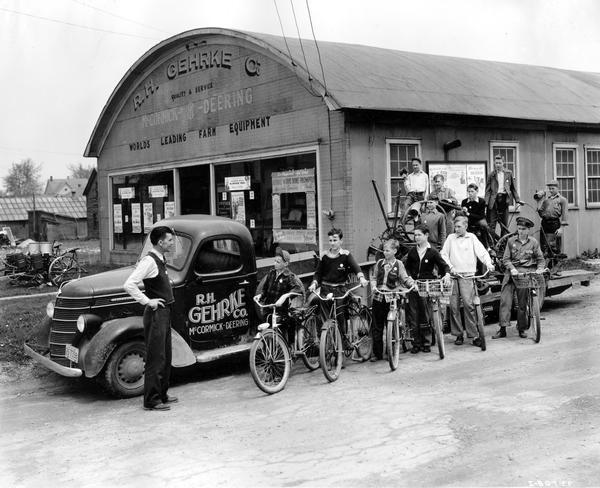 WW II scrap metal drive. Scoutmaster Edward G. Shaw and his troop of boy scouts on bicycles and on a trailer loaded with scrap metal. The trailer is hitched to an International truck and is parked in front of a McCormick-Deering dealership operated by R.H. Gehrke Company. The Scouts helped collect scrap metal during Governor Julius P. Heil's MacArthur Week. The troop of eighteen boys was divided in four divisions and the boys went out among the farms on their bicycles. They stopped at various farms, asked permission to collect scrap and, when it was granted, gathered it in convenient piles to be collected later by the junk dealer's motor truck.