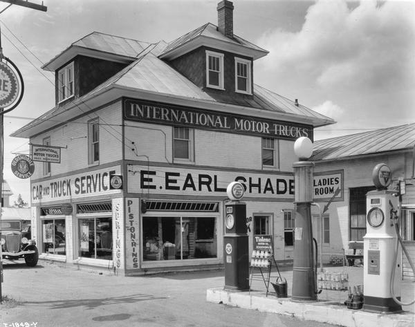 International motor truck dealership and service station of E. Earl Shade. Also attached is a gas station island with Purol Pep and Conoco pumps. The station also serviced Oldsmobile cars.