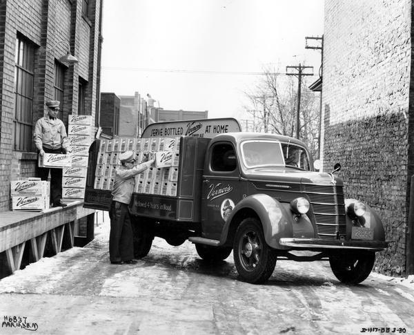 Two men loading cases of Vernon's ginger ale (soda) on an International D-30 truck in Toronto, Canada.