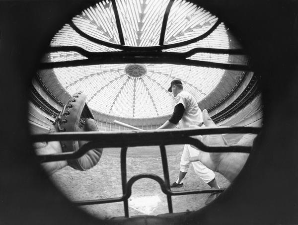 Paneled dome of Houston's Astrodome as seen through a baseball catcher's mask behind home plate.