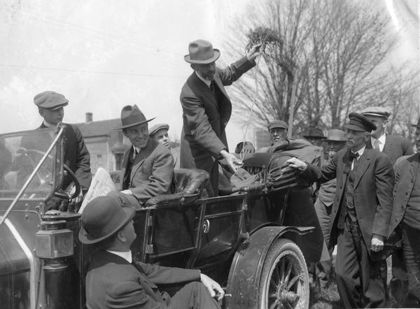 Professor Holden of International Harvester's Agricultural Extension Department expounds the benefits of alfalfa from the back seat of a car.