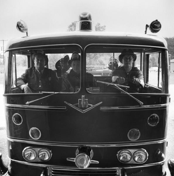 Five fire fighters en route to a fire in an International Model CO-8190 1963 fire truck.