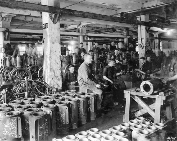 Workers look on as machine parts are tested at International Harvester's Milwaukee Works. This photograph was displayed at the 1915 Panama-Pacific International Exposition in San Francisco. The factory was owned by the Milwaukee Harvester Company until 1902.