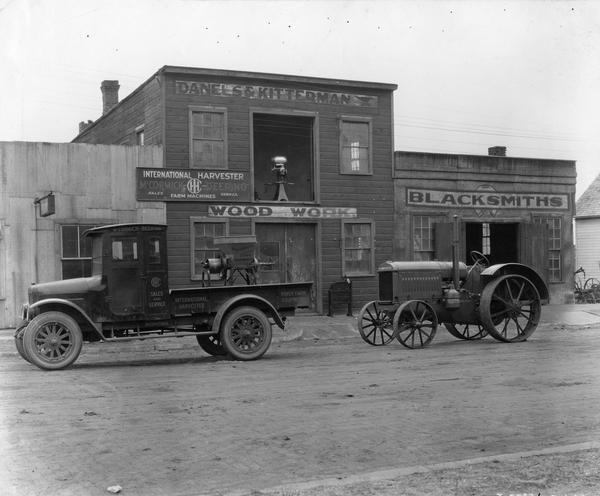 International "Red Baby" (Model S) truck and McCormick-Deering 10-20 tractor in front of the dealership of Danels & Kitterman.  In the back of the truck is a McCormick-Deering feed grinder. Pictured in the background in the open second floor window is a McCormick-Deering cream separator.