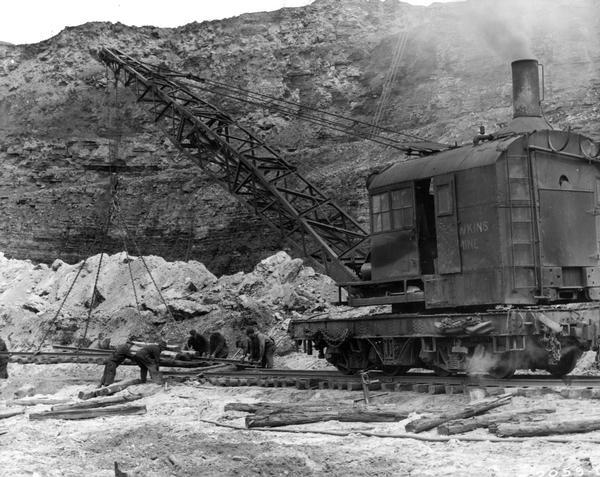 Workers and a steam railroad crane laying rails for International Harvester's Hawkins Mine.