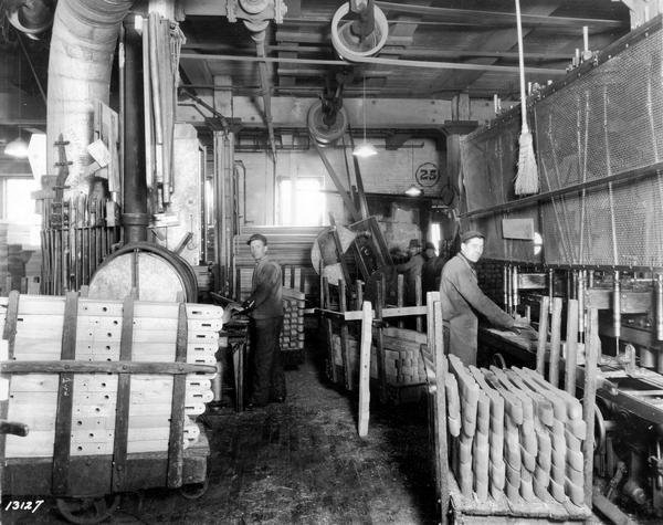 Workers manufacturing wooden wagon components inside International Harvester's Weber Wagon Works. One worker is drilling holes in wooden pieces. The factory was located at Auburn Park and was owned by the Weber Wagon Company until 1904. International Harvester produced wagons at the factory until 1927.