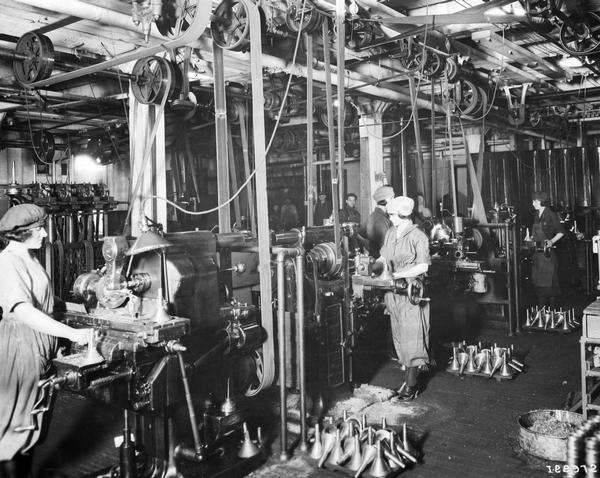 Female factory workers machining parts for cream separators and International Harvester's Milwaukee Works. An original caption identifies them as "Milwaukee Works Dairy Maids." The factory was owned by the Milwaukee Harvester Company until 1902.