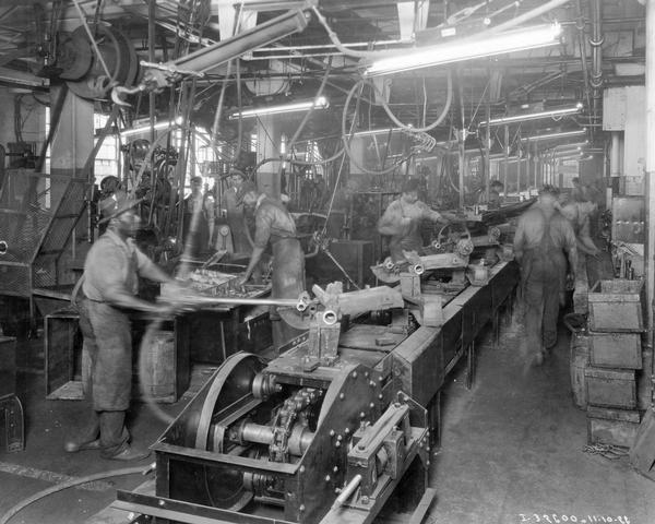 Workers, including some African Americans, assembling mower gear housings along an assembly line at International Harvester's McCormick Works. The factory was in operation from 1873-1961 and was located at Blue Island Avenue and Western Avenue in the Chicago subdivision called "Canalport."