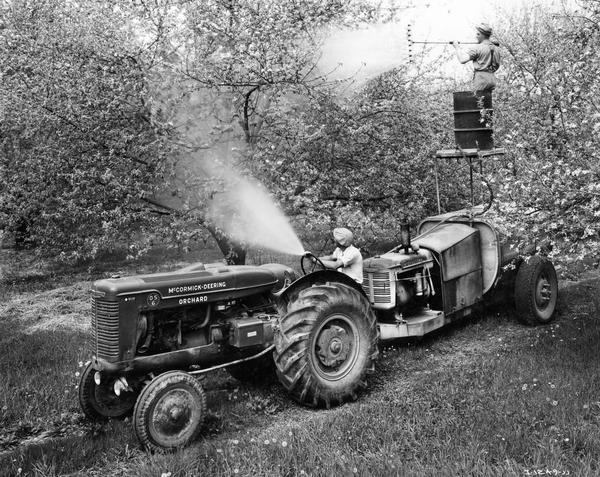 McCormick-Deering Model OS-6 orchard tractor in operation in an apple orchard with a 500 gallon Hardie Spray Rig. The rig had a 30-35 gallon pump capacity and was equipped with an International Model U-2 power unit. The equipment was owned and operated by John Humphreys, pictured here on the scaffold atop the spray unit.