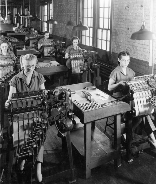 Slightly elevated view of female workers operating machines at International Harvester's Chatham Works in Ontario, Canada. The factory was originally owned by the Chatham Manufacturing Company. It was purchased by the International Harvester Company in 1910.