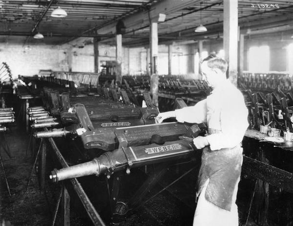 Worker adding pin striping to parts of wagon trucks at International Harvester's Weber Wagon Works in Auburn Park. The factory was owned by the Weber Wagon Company until 1904, when it was purchased by International Harvester.