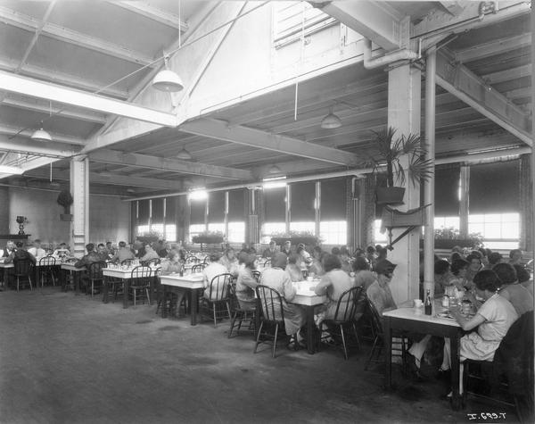 Male and female workers eating lunch inside the cafeteria at International Harvester's Hamilton Twine Mills, Hamilton, Ontario, Canada.