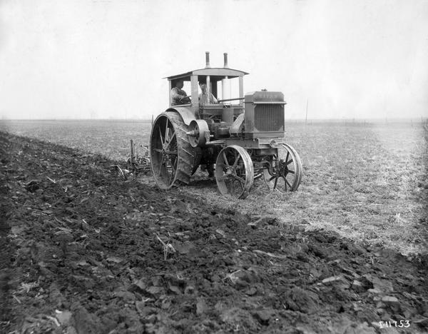 Two men pulling a plow with a Titan 12-25 tractor. The tractor became known as the International 15-30 after 1917.