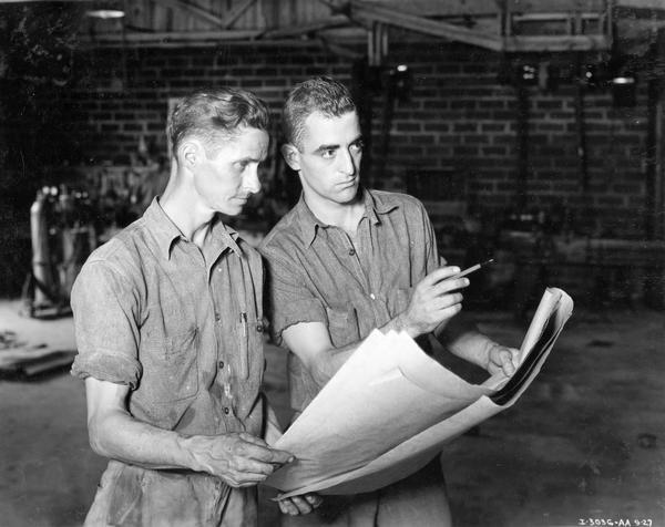 Two men consulting a set of plans as part of a  store modernization project at an International Harvester dealership.