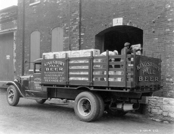 Men loading crates of Kingsbury Pale Beer onto an International B-4 truck outside the Kingsbury Beverage Company. The truck had a 170-inch wheelbase. The wooden crates bear the name "Manitowoc Products Co., Manitowoc, Wisconsin".