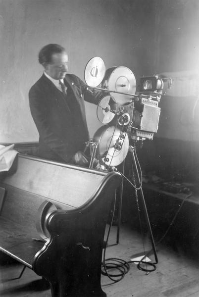 Rural evangelist John E. Zoller with a Zenith projector and stereopticon with a DeVry generator used during sermons. Original caption reads: "We show excellent pictures, clear and distinct, and we can show them anywhere. Such an outfit is indispensable to the rural worker."