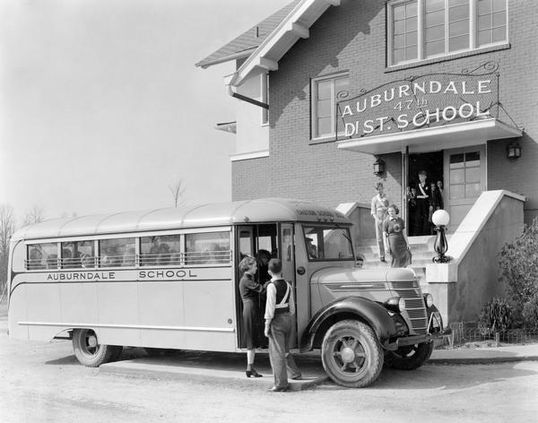 Students boarding an International D-30 school bus outside the Auburndale 47th District School in Jefferson County. Some students appear to be dressed as crossing guards. The bus featured a 191-inch wheelbase and a Wayne body.