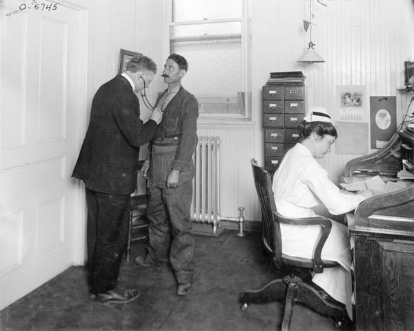 Factory worker having his chest examined by a doctor inside a medical office at International Harvester's Auburn Works (formerly known as "Osborne Works"). The factory was owned by D.M. Osborne Company before 1906.