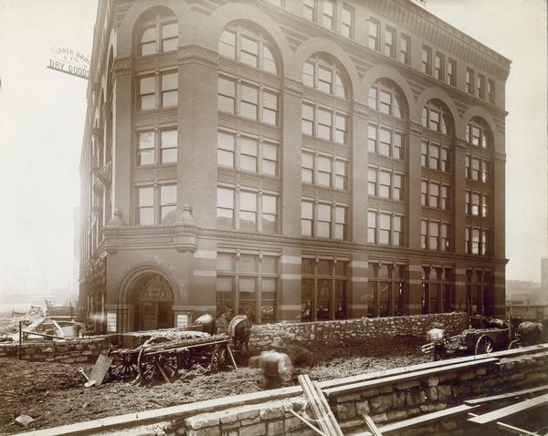 Construction work in the streets outside the offices of the McCormick Harvesting Machine Company located at 212 Market Street. Two horse-drawn wagons and several construction workers are outside the building. This building served as the McCormick Company's general office from 1885 to 1891.