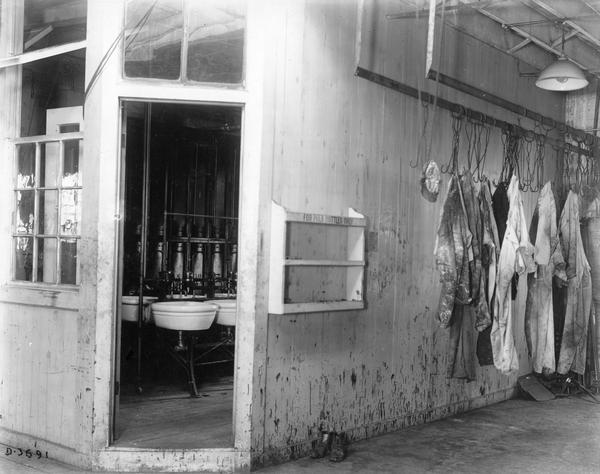 Wash room in the paint shop at International Harvester's Deering Works. Paint-splattered clothes are hanging outside the room.