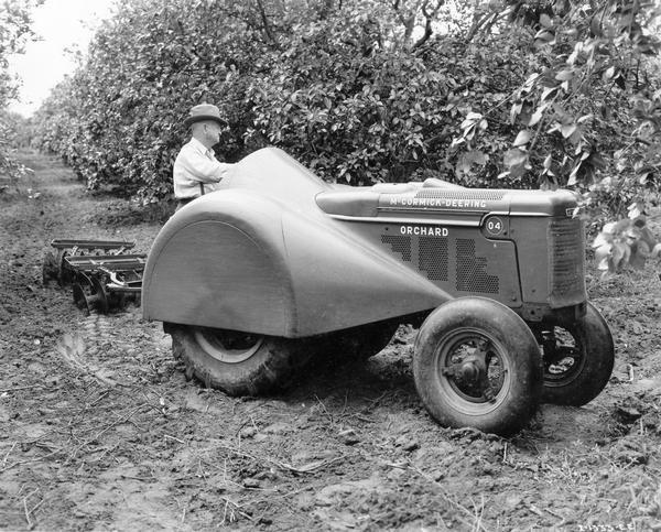 Farmer in Grove with O-4 Orchard Tractor Farmer operating a McCormick-Deering O-4 orchard tractor and disc harrow.