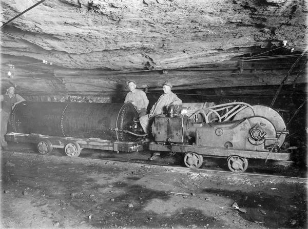 Three miners with a mine sprinkler inside a mine shaft. Benham was a "company town" created by International Harvester for the workers of the Wisconsin Steel Company. Wisconsin Steel was a subsidiary of International Harvester and operated coal mines at Benham.
