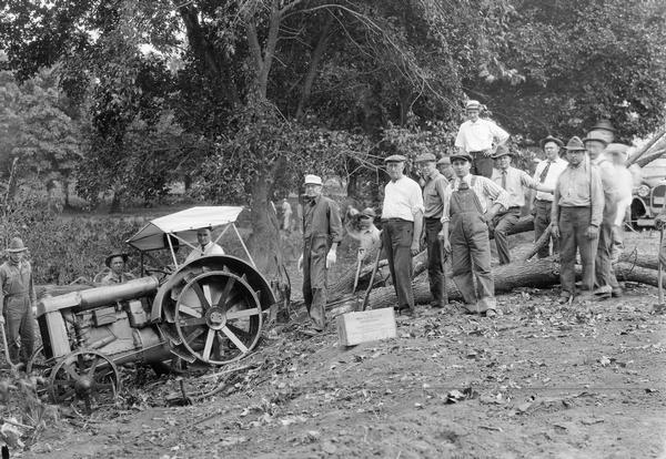 Original caption reads: "Members of Marshalltown Club at work on township road near Marshalltown, IA (1920). Over fifty members of the Club contributed a day's work to improving the road leading to town. For the privilege of giving this day's work, each volunteer paid $10 into the Club's special road fund, the money to be used in improving township roads, for which work the county road fund cannot be used. After these business men graded this piece of road, farmers graveled it. Thus a spirit of cooperation was established." The men are using a Fordson tractor.
