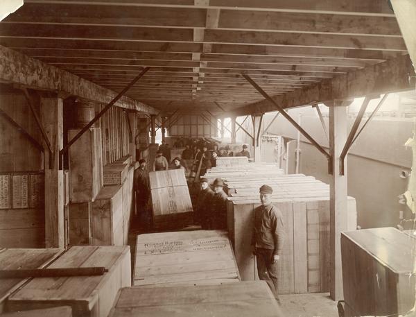 Dock workers preparing boxed farm machines for loading onto a ship at the McCormick Reaper Works dock. The boxes contain McCormick Daisy reapers, New 4 mowers, and let hand open grain elevators. The crates are stamped with the destination(?) "Liverpool". The McCormick Reaper Works was owned by the McCormick Harvesting Machine Company until 1902 when it became the International Harvester Company's "McCormick Works." The factory was located at Blue Island and Western Avenues in the Chicago subdivision called "Canalport." It was closed in 1961.