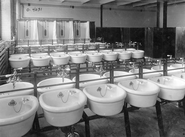 Rows of gleaming white sinks and shower stalls in the wash room for the "malleable shop" at International Harvester's Osborne Works. The factory was owned by the D.M. Osborne Company until 1903, when it was purchased by International Harvester. The factory was later known within the company as the "Auburn Works." It was located at 5 Pulaski Street.