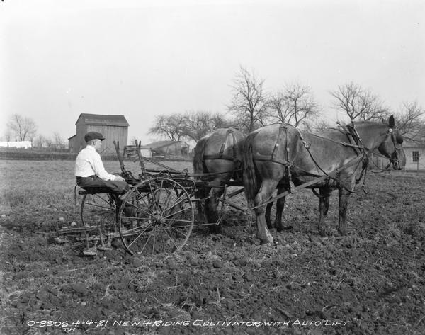 Boy cultivating a field with a horse-drawn New No. 4 riding cultivator with auto lift.