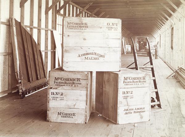 Shipping crates at the McCormick Harvesting Machine Company factory. The crates contain a Little 4 mower bound for Anderson & Mattson of Malmo, a McCormick Folding Daisy Reaper bound for Julius Aberle of Jaffa, Palestine, and another Folding Daisy Reaper bound for Odessa, Russia.