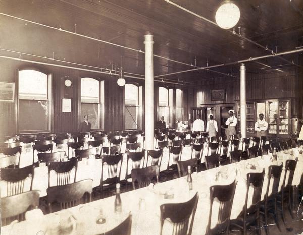 Dining hall at International Harvester's McCormick Works. The factory was owned by the McCormick Harvesting Machine Company before 1902. The staff of the dining hall are lined up in the background.