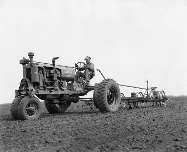 Farmer Glenn Brutus planting corn with a Firestone-equipped Farmall F-30 tractor and a four-row McCormick-Deering planter.