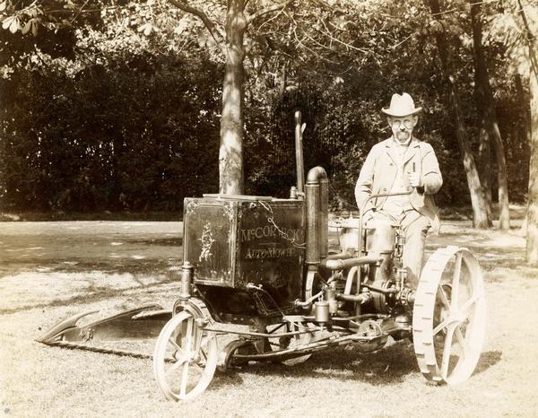 Man sitting in a McCormick Auto-Mower at or near the Paris Exposition in France. The Auto-Mower was an experimental gasoline-powered mowing machine. This is one of two Auto-Mowers produced by the company. This machine had a two-cylinder engine. The other machine had a single-cylinder engine.