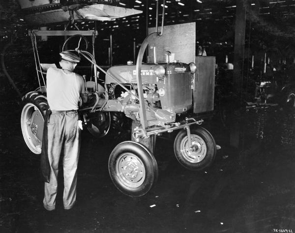 Factory worker completing assembly of a Farmall Cub tractor at International Harvester's Louisville Works.