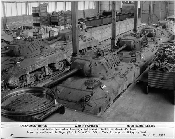 M-7 tanks in storage on the shipping dock at International Harvester's Bettendorf Works. Original caption reads: "Looking southwest in Bays #7 and 8 from Col. 708 - Tank Storage on Shipping Dock."