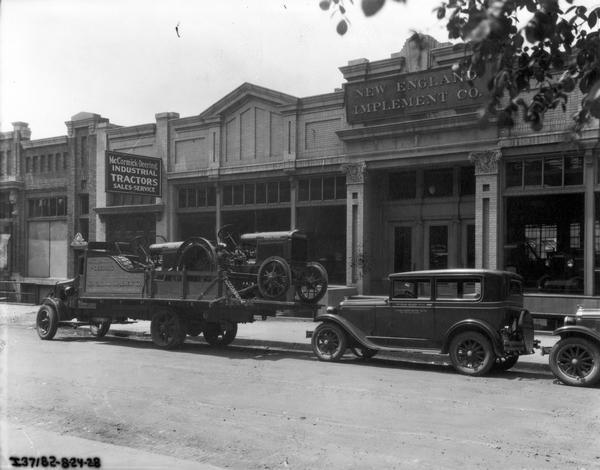 Three International service trucks, one loaded with a McCormick-Deering industrial tractor, in front of the New England Implement Co., Boston(?), Massachusetts. The New England Implement Co. was a dealer and service center for International Harvester tractors and equipment.