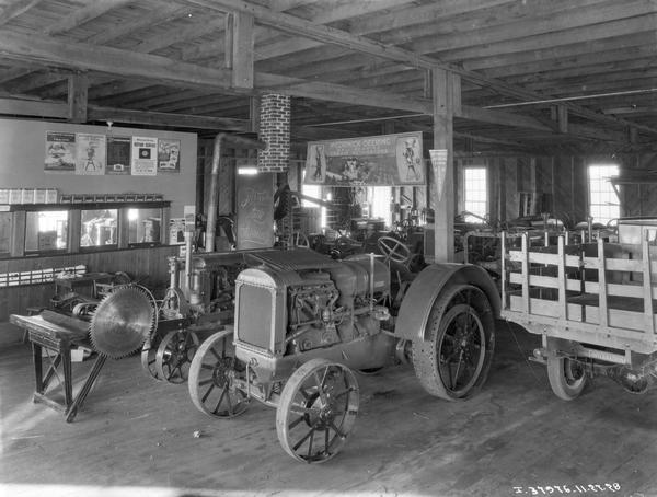 McCormick-Deering industrial tractor, a Farmall Regular tractor and other machinery on display in an International Harvester dealership showroom. A large cream separator poster is hanging from the ceiling.