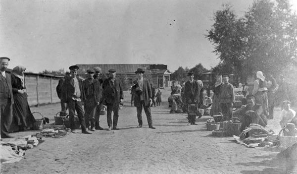 Men, women, and children in a street market with baskets of produce in Russia, probably near Lubertzy.
