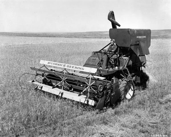 Slightly elevated view of fifteen-year-old Peggy Wold operating a McCormick-Deering 123-SP (self-propelled) harvester-thresher (combine) on the farm of Carl Gullard.