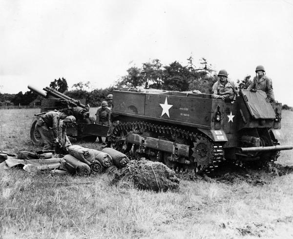 Soldiers pulling 155mm howitzer with an M-5 tractor at Camp Adair, Oregon. The original caption reads:  "This is the new M-5 tractor which replaces 2 and one-half ton trucks as the standard prime-mover for the big new 155 mm howitzers. The tractor jockey is rated a member of the gun-crew of 10 men crew members (background) are picking up trails of gun preparatory to hooking on."