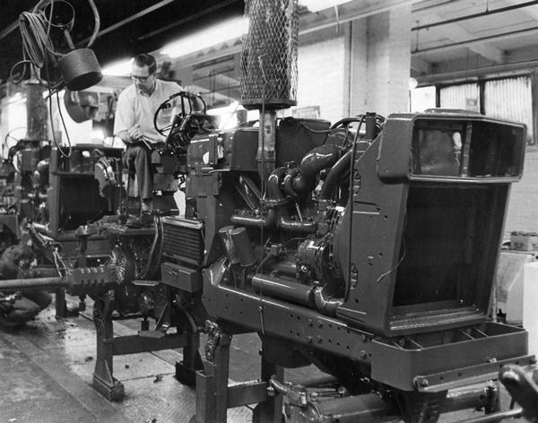 Factory worker on a tractor on an assembly line at International Harvester's Farmall Works (factory).