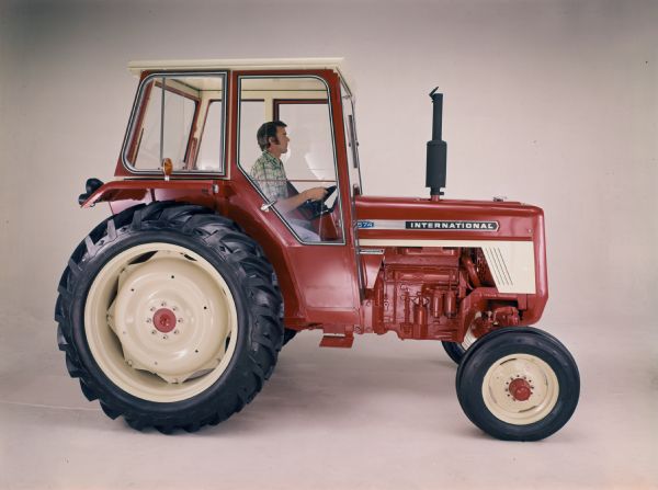 Color studio photograph of a man sitting in an International 574 tractor.