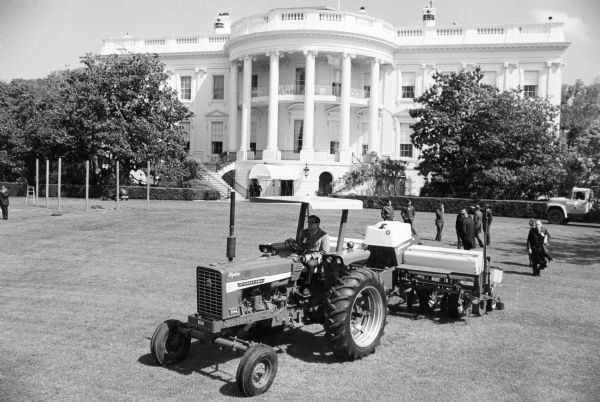 Slightly elevated view of a man driving an International 544 tractor and equipment on the White House lawn for national "Salute to Agriculture" day.