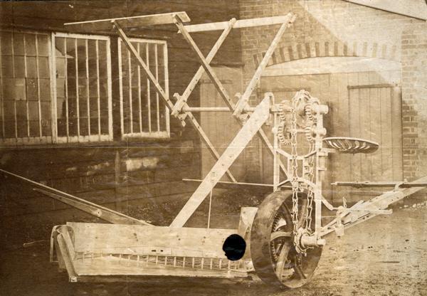 McCormick self-rake reaper as manufactured in the 1860s. The reaper is sitting in the yard of the McCormick Reaper Works (factory). Original caption reads: "Taken in the McCormick Works before the Chicago Fire of 1871."