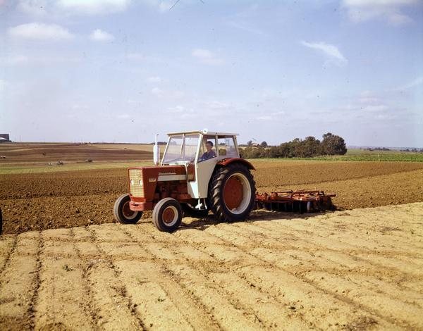 Color photograph of a man plowing a field in Germany with a McCormick 624 tractor and disk plow.