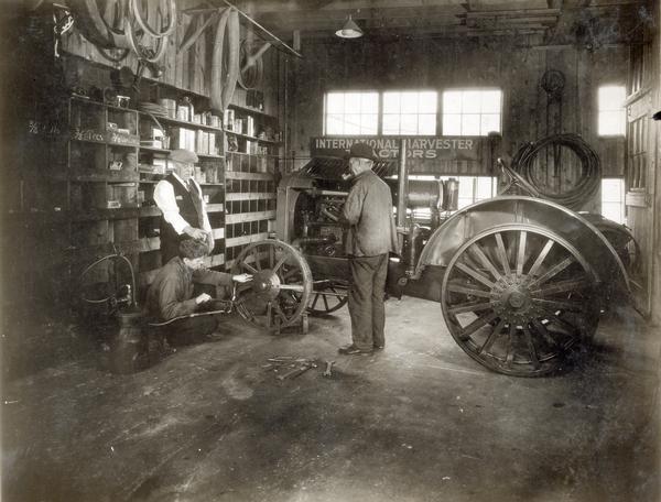 Mechanic working on the front wheel of an International tractor in service shop of the International Harvester dealership of Dan Pullin and Son.