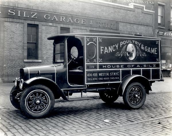 S-speed truck owned by House of A. Silz and parked on the street in front of Silz Garage. The side panel of the truck includes an advertisement for "Fancy Poultry and Game."