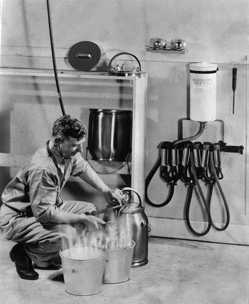 A man demonstrates how to use a McCormick-Deering milking machine.